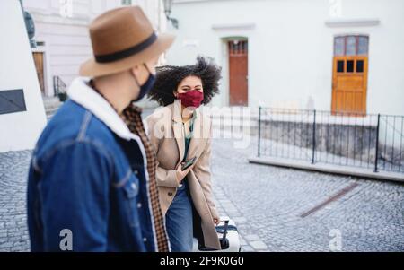 Young couple tourists with luggage walking on streets in old town, coronavirus concept. Stock Photo