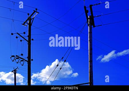 Telephone poles line and power cables against deep blue sky and white cumulus cloud Stock Photo