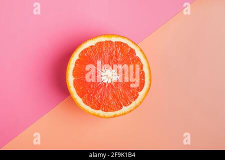 Half of grapefruit on orange and pink background. Stock Photo