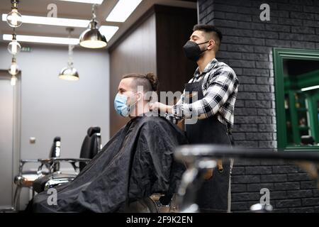 Man client visiting haidresser in barber shop, coronavirus and new normal concept. Stock Photo