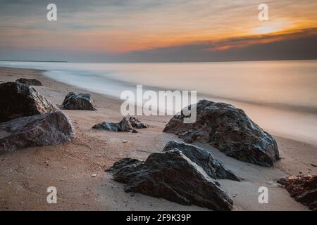 long exposure Sea rocks Magnificent sunrise view at sunrise Romantic atmosphere in peaceful morning at sea. Pink horizon with first hot sun rays. Stock Photo