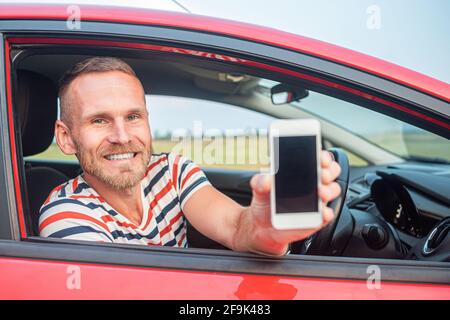 The driver shows a smartphone with a blank screen. Stock Photo