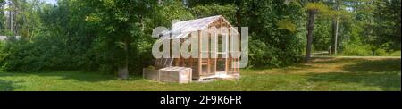 Panoramic view of a wooden domestic greenhouse for growing vegetables Stock Photo