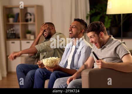 male friends with popcorn watching tv at home Stock Photo