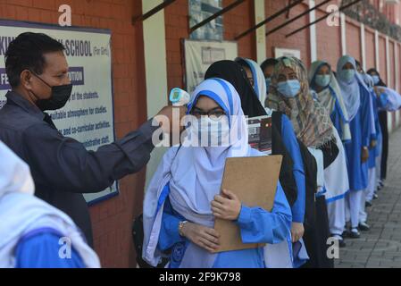 Lahore, Pakistan. 19th Apr, 2021. A security guard is checking the body temperature and sanitizing the shoes of girls students before entering in the educational Institutes. Government Kinaird girls high school from grade 9th to 12th is reopen after long vacation due to the third phase of Covid-19 in Lahore. (Photo by Rana Sajid Hussain/Pacific Press) Credit: Pacific Press Media Production Corp./Alamy Live News Stock Photo
