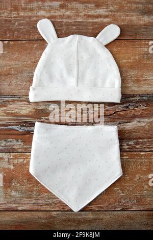 baby hat with ears and bib on wooden table Stock Photo