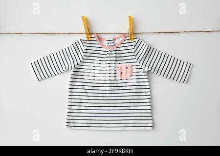 shirt for baby girl hanging on rope with pins Stock Photo