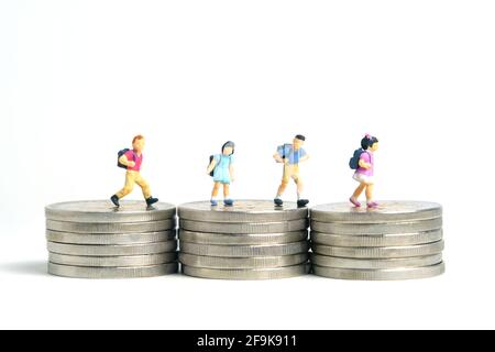 School admission budget.  Children or kids, walking above golden coin money stack. Miniature tiny people toys photography. isolated on white backgroun Stock Photo