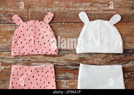 baby hats with ears and bibs on wooden table Stock Photo