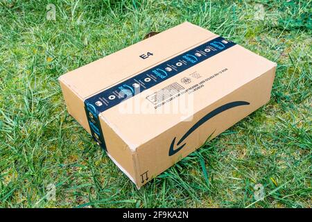 Nice, France- 14.04.2021: View from above of Amazon Prime logotype printed on cardboard box security scotch tape on the front. Green grass background. Stock Photo