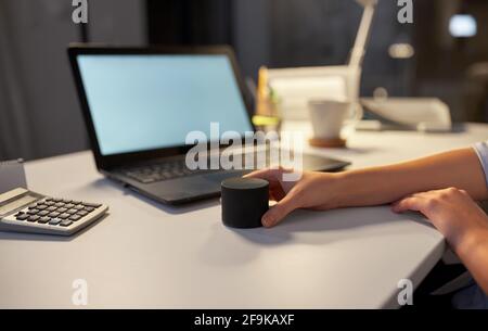 hand using smart speaker at night office Stock Photo