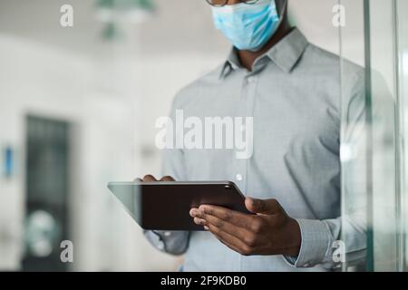 African businessman in a face mask using a digital tablet Stock Photo