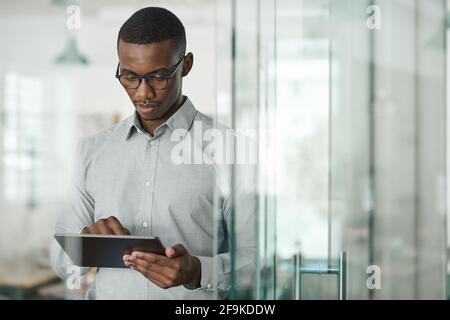Focused young African businessman using a digital tablet at work Stock Photo
