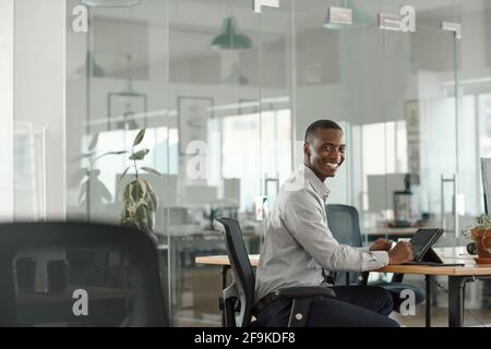 Smiling young African businessman using a digital tablet at work Stock Photo