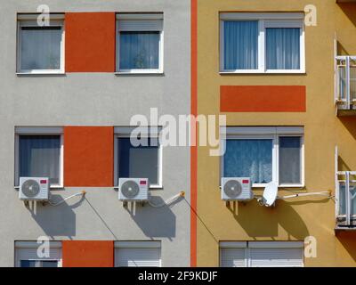 air conditioning wall installed condenser units. cooling corcept. residential windows on apartment building exterior wall or facade. stucco elevation Stock Photo