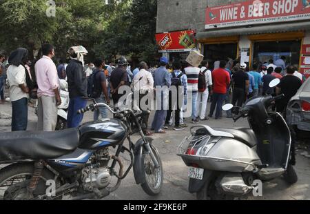 People flout social distancing norms as they stand in queue to buy liquor at a wine and liquor store ahead of the 7 days lockdown imposed by New Delhi government.Delhi Chief Minister Arvind Kejriwal announces to impose a lockdown from 10pm tonight for 7 Days to tackle the rising Covid-19 cases in the capital city. Stock Photo