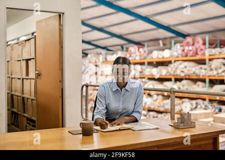Young African woman working at her desk in a warehouse Stock Photo