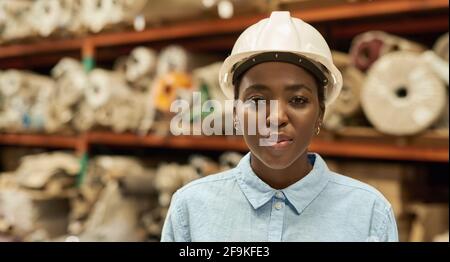 Young African woman wearing a hardhat standing in a warehouse Stock Photo