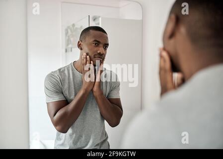 Young African American man touching his face in his bathroom Stock Photo