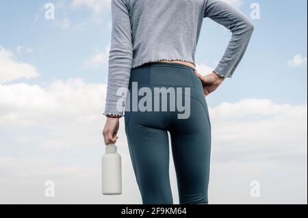 Rear view of a sporty woman holding a bottle of water. Close up. Stock Photo