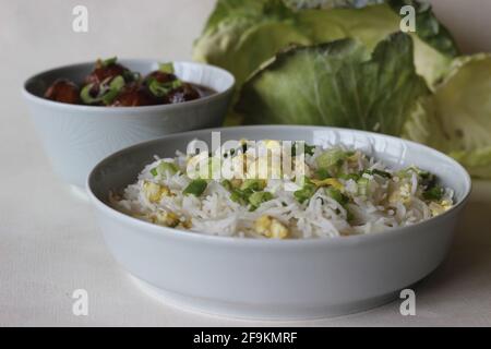 Steamed basmati rice with scrambled eggs and spring onions, called egg rice served along with Vegetable Manchurian. Shot on white background Stock Photo