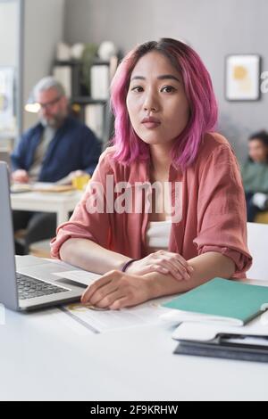 Portrait of Asian student looking at camera while sitting at the table and working on laptop Stock Photo