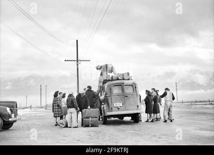 Man loading Bus with Luggage while Group of Japanese-American wait to leave Manzanar for Relocation, Manzanar Relocation Center, California, USA, Ansel Adams, Manzanar War Relocation Center Collection, 1943 Stock Photo