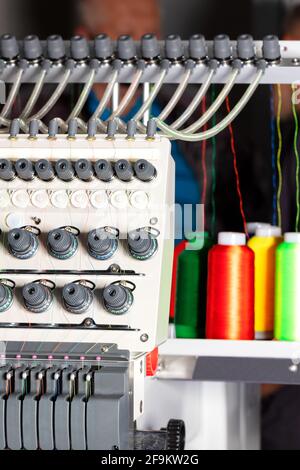 Fragment of an industrial embroidery machine with multi-colored threads in a blur, close-up. Stock Photo