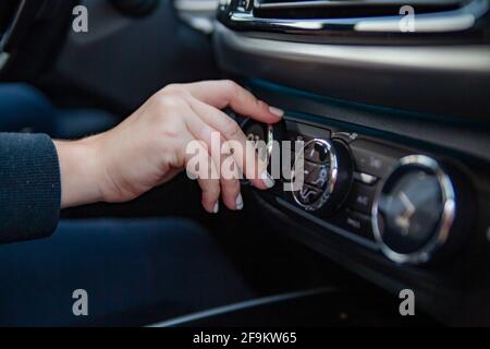 a woman's hand turns the knob for adjusting the climate control system in a modern premium car. setting a comfortable temperature in the car. travel b Stock Photo