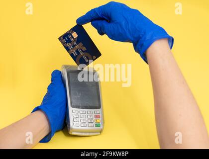 A business makes an electronic payment with a credit card with protection of gloves by the corona virus Stock Photo