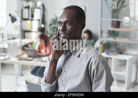 African young businessman talking on mobile phone while working at office Stock Photo