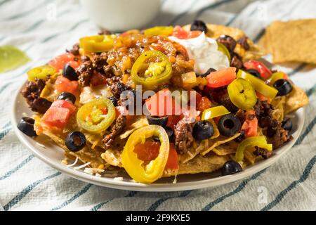 Homemade Cheesy Beef Nachos with Olives and Jalapenos Stock Photo