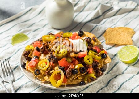 Homemade Cheesy Beef Nachos with Olives and Jalapenos Stock Photo
