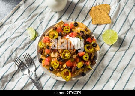 Homemade Cheesy Beef Nachos with Olives and Jalapenos Stock Photo