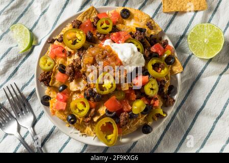 Homemade Cheesy Beef Nachos with Olives and Jalapenos Stock Photo