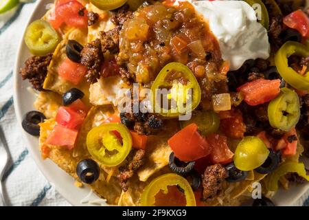 Homemade Cheesy Beef Nachos with Olives and Jalapenos Stock Photo