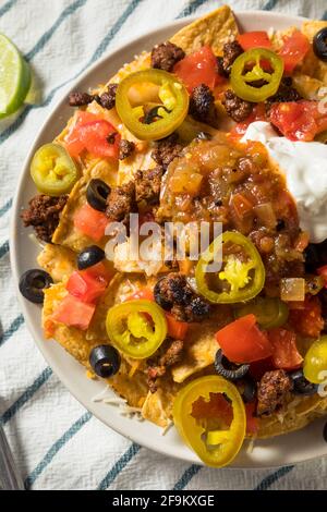 Homemade Cheesy Beef Nachos with Olives and Jalapenos Stock Photo