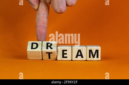 Dream team symbol. Businessman turns cubes and changes the word 'dream' to 'team'. Beautiful orange table, orange background. Business and dream team Stock Photo