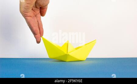 Image of businessman pushing paper made origami boat forward in a conceptual image. Over blue and white background with copy space. Business concept. Stock Photo