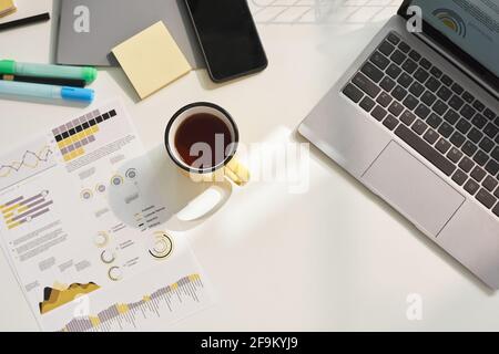High angle view of cup of coffee on the table with laptop and documents on it at office Stock Photo