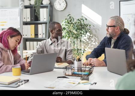 Group of business people sitting at the table with computers and working in team at office Stock Photo