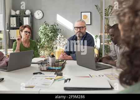 Business people sitting at the table with laptops and working in team at business meeting Stock Photo