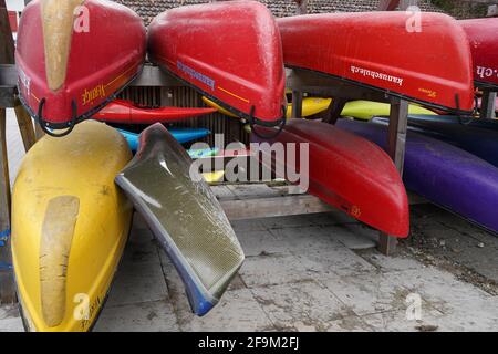 Kayaks and canoes stored in racks upside down in front view close up. They wait for start of water sport season. Stock Photo