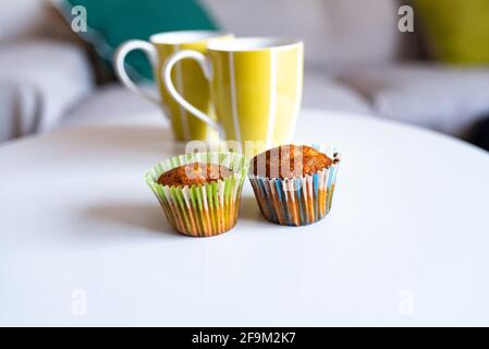 Muffins with colored wrappers and green cups on top of a white table Stock Photo