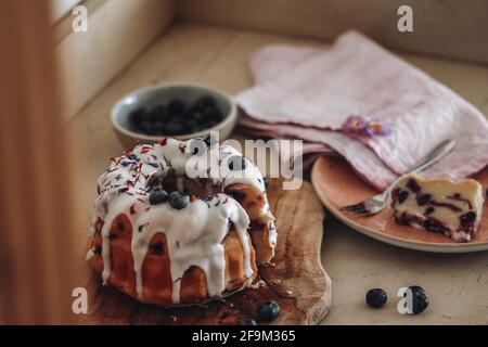 Mini bundt cake topped with glaze nad berries on a wooden board Stock Photo