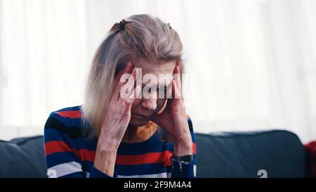 Elderly woman having a headache. Massaging temples. High quality photo Stock Photo