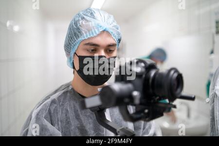 Young operator in medical protective suit with camera Stock Photo