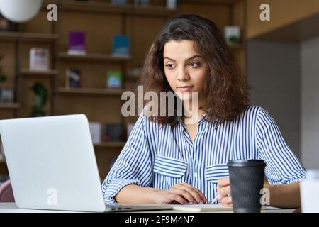 Young latin indian student using laptop watching online virtual training. Stock Photo