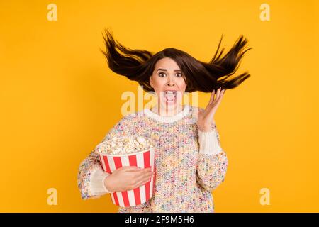 Photo of scared crazy young woman fly hair wind hold pop corn bucket horror movie isolated on yellow color background Stock Photo