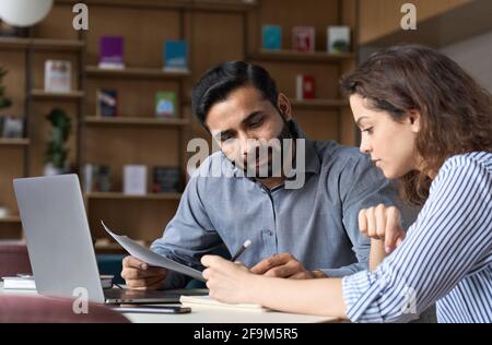 Two multiethnic professionals working together with laptop in office. Stock Photo